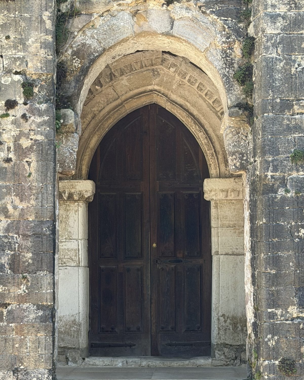 A weathered stone archway framing a heavy wooden door